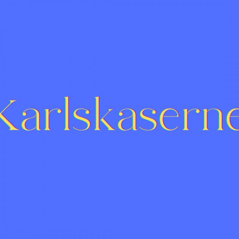 Gelber Schriftzug „Karlskaserne“ auf einem hellblauen Hintergrund.